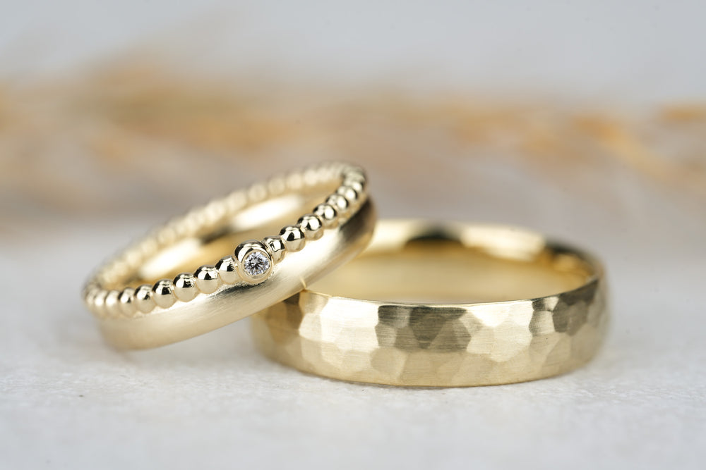 Eheringe in Gelbgold mit gehämmerter Oberflaeche und Perlen am Damenring mit Stein