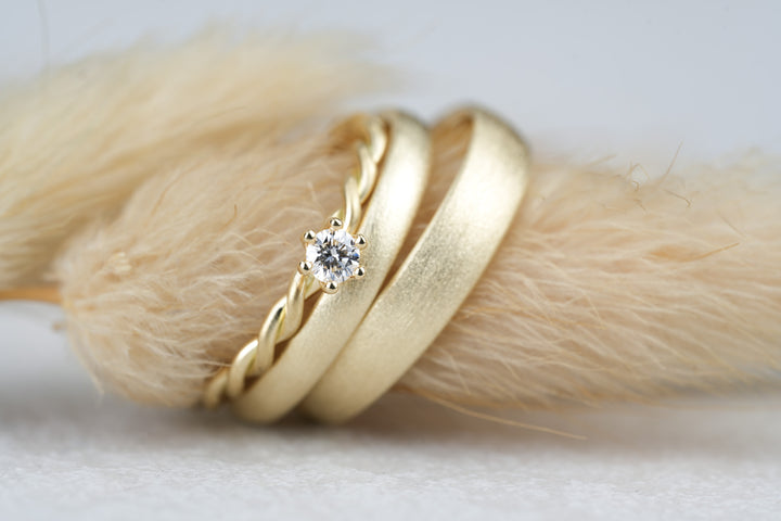 besondere Eheringe aus Gold mit Verlobungsring als Kordelrin mit Stein