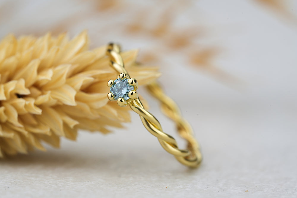 gedrehter Verlobungsring in Gold mit blauer Diamant